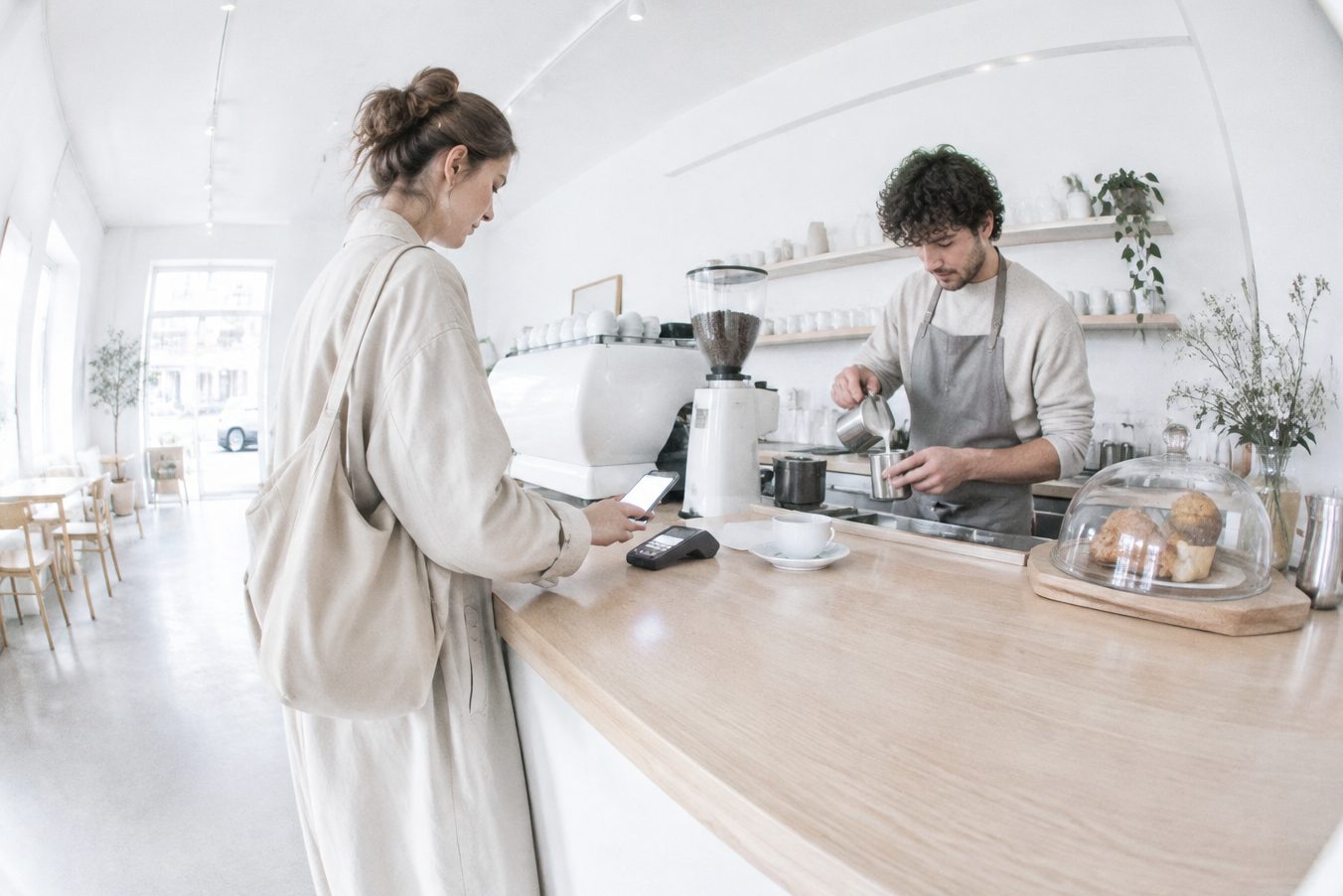 A customer pays with her phone at a coffee shop counter