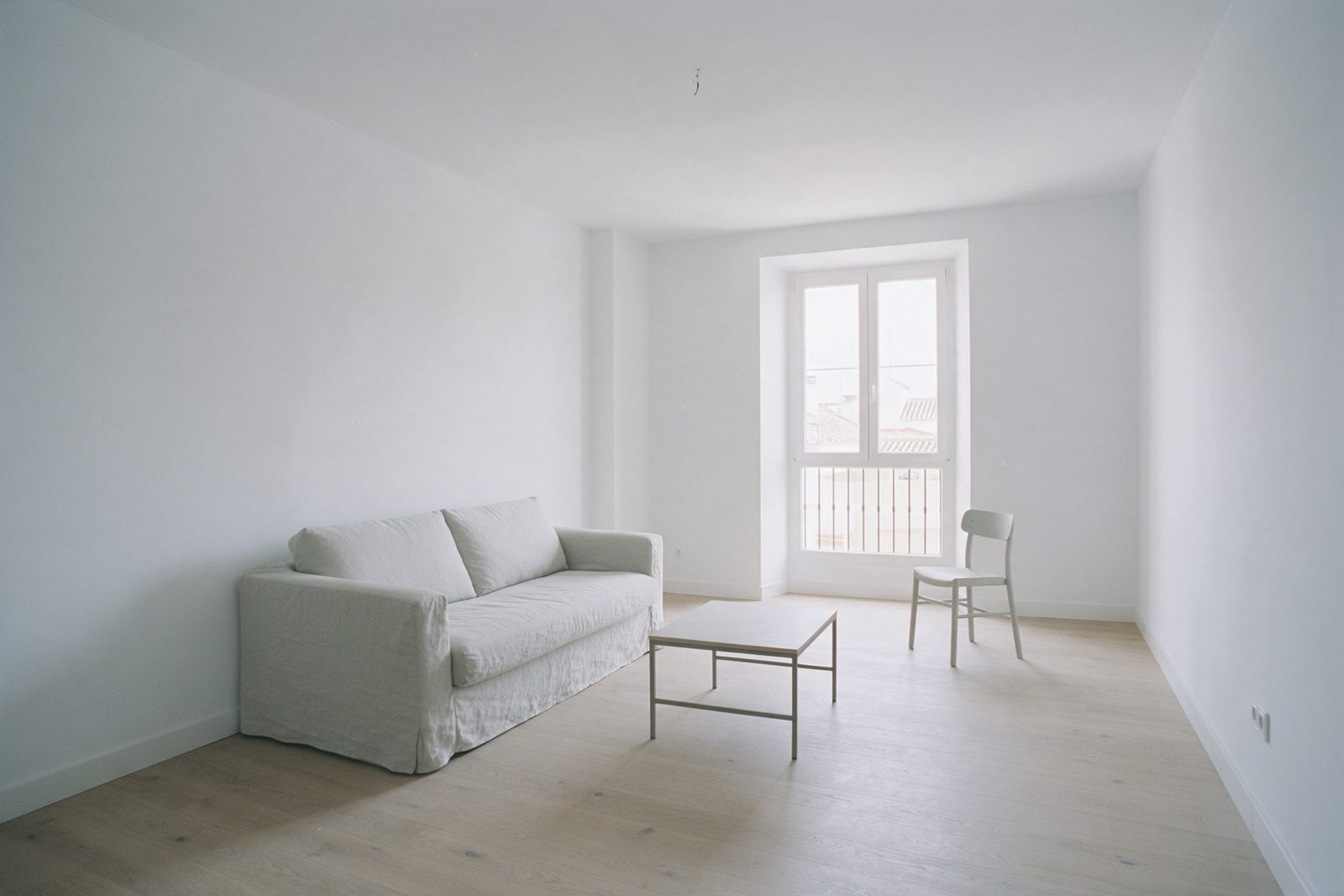 Bright living room in a renovated apartment, with a sofa, coffee table, and balcony