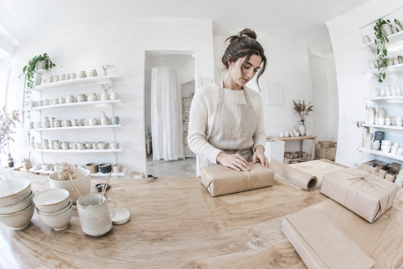 A person packs orders with kraft paper at the counter of a ceramic store