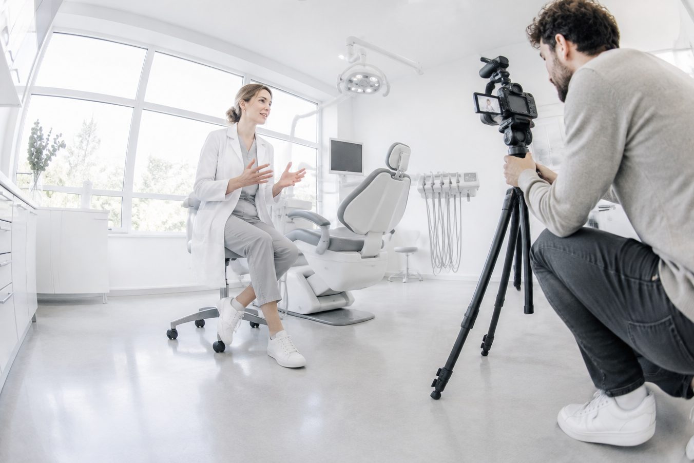 A dentist speaks to a video camera in her office